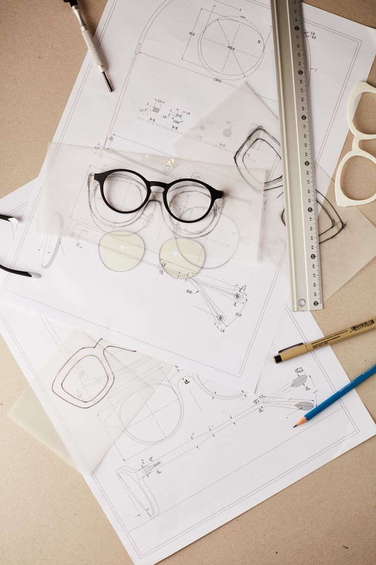Technical drawings, prototype frames, and lenses on a design desk.